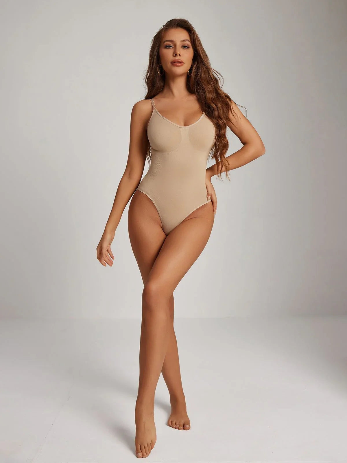 Woman modeling Formivelle nude seamless bodysuit shapewear in a minimalist studio setting.